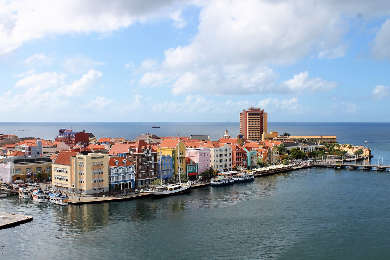 Vue aérienne du port de Curaçao avec des maisons colorées et des bateaux.