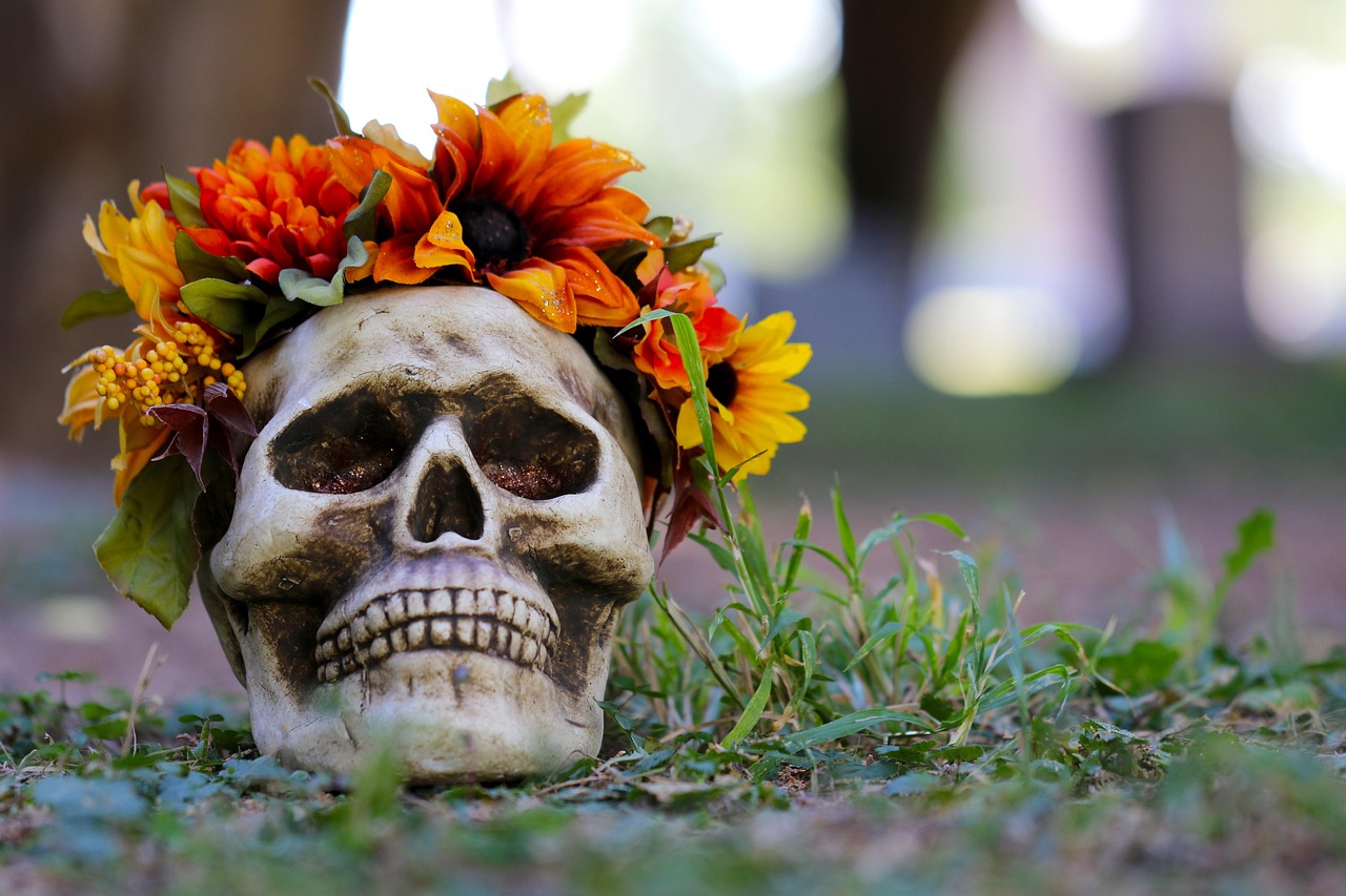 Tête de mort déposée sur le sol avec une couronne de fleurs oranges.