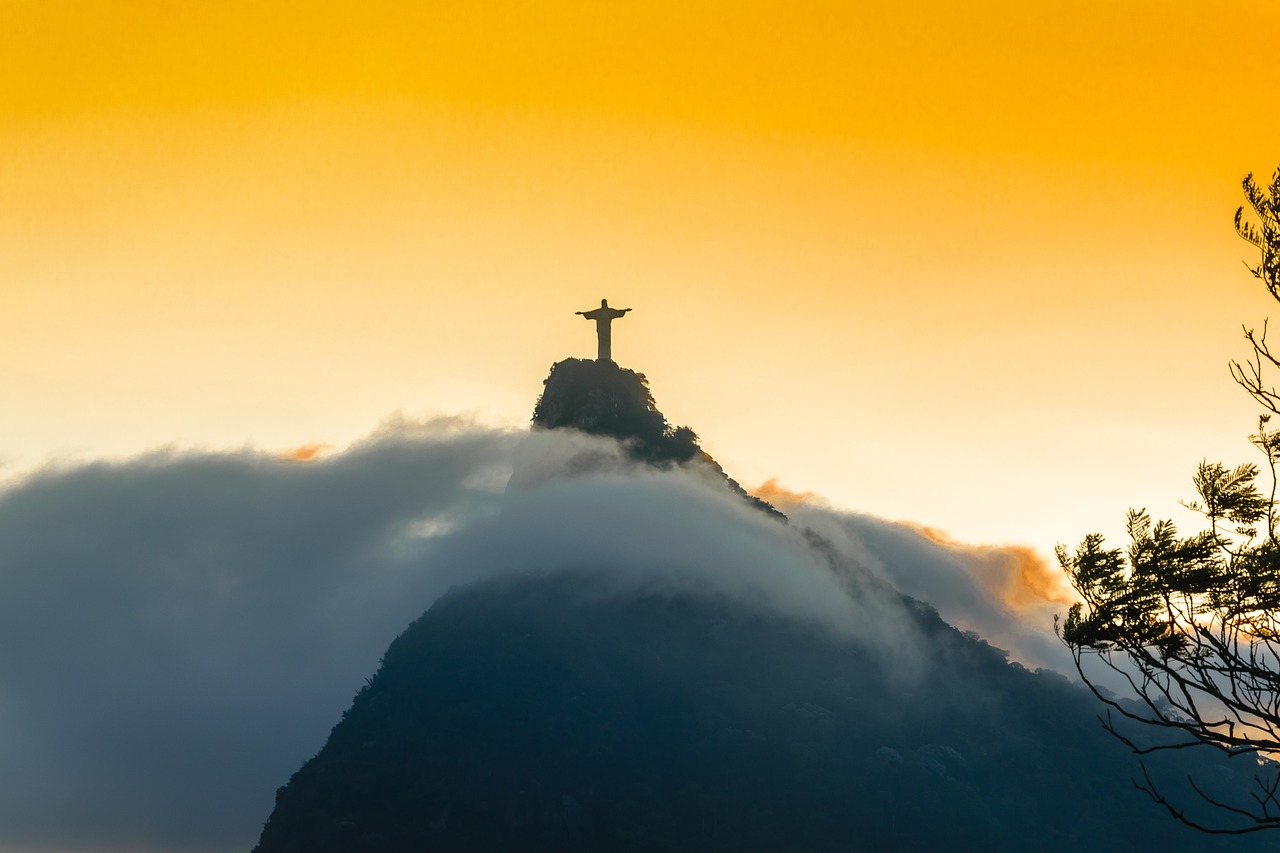 Statue du Christ Rédempteur sur la montagne entourée de nuages sur un fond d'un couchée de soleil à Rio de Janeiro.