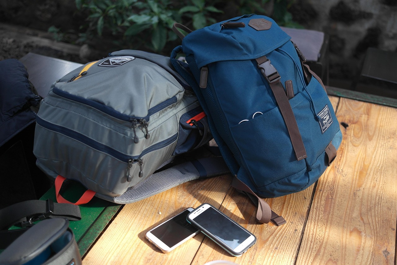 Un sac à dos bleu et un sac à dos gris sur une table de bois.